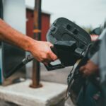 A driver holding a fuel nozzle at a petrol station