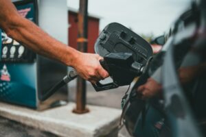 A driver holding a fuel nozzle at a petrol station