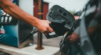 A driver holding a fuel nozzle at a petrol station
