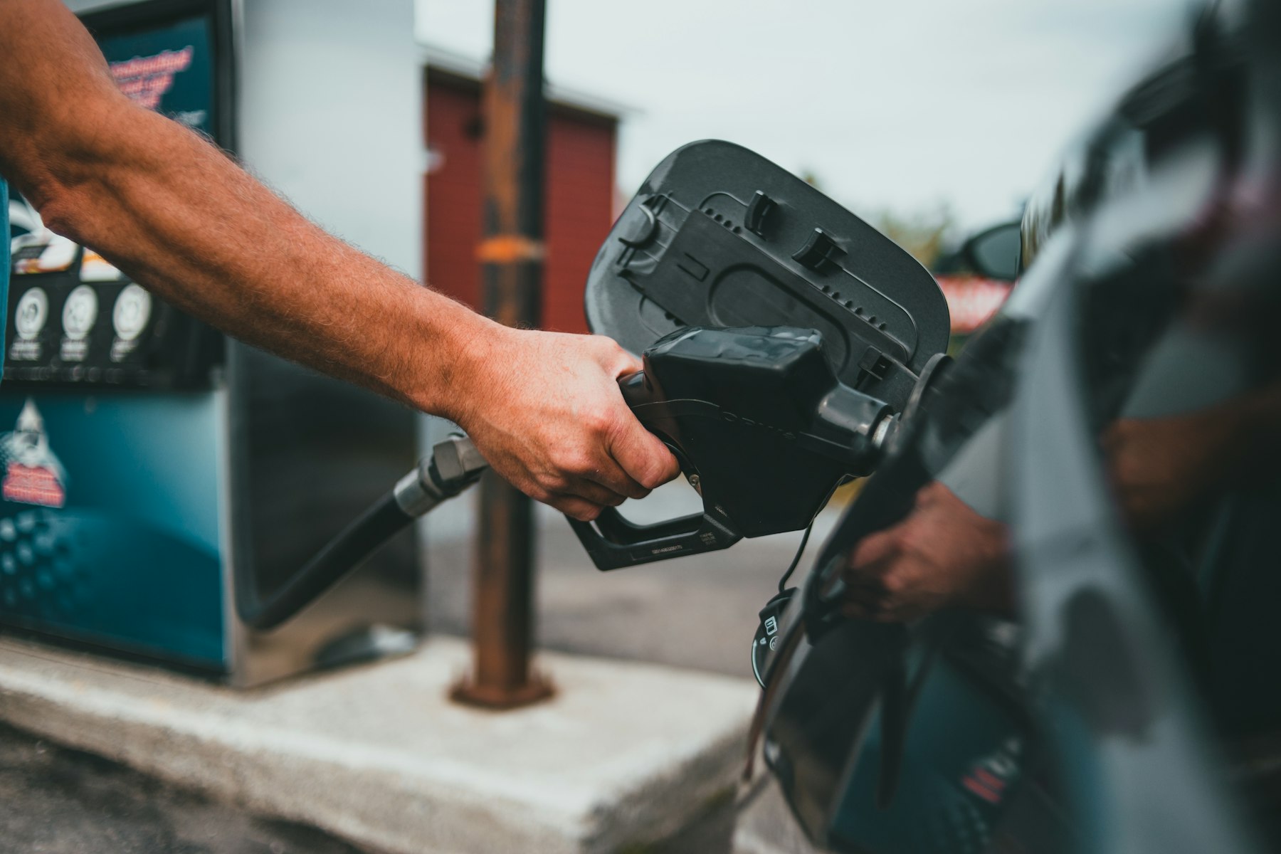 A driver holding a fuel nozzle at a petrol station